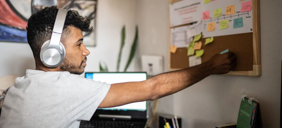 Person wearing headphones, placing sticky notes on a board